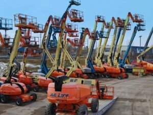 Multiple boom lifts parked in an outdoor lot.