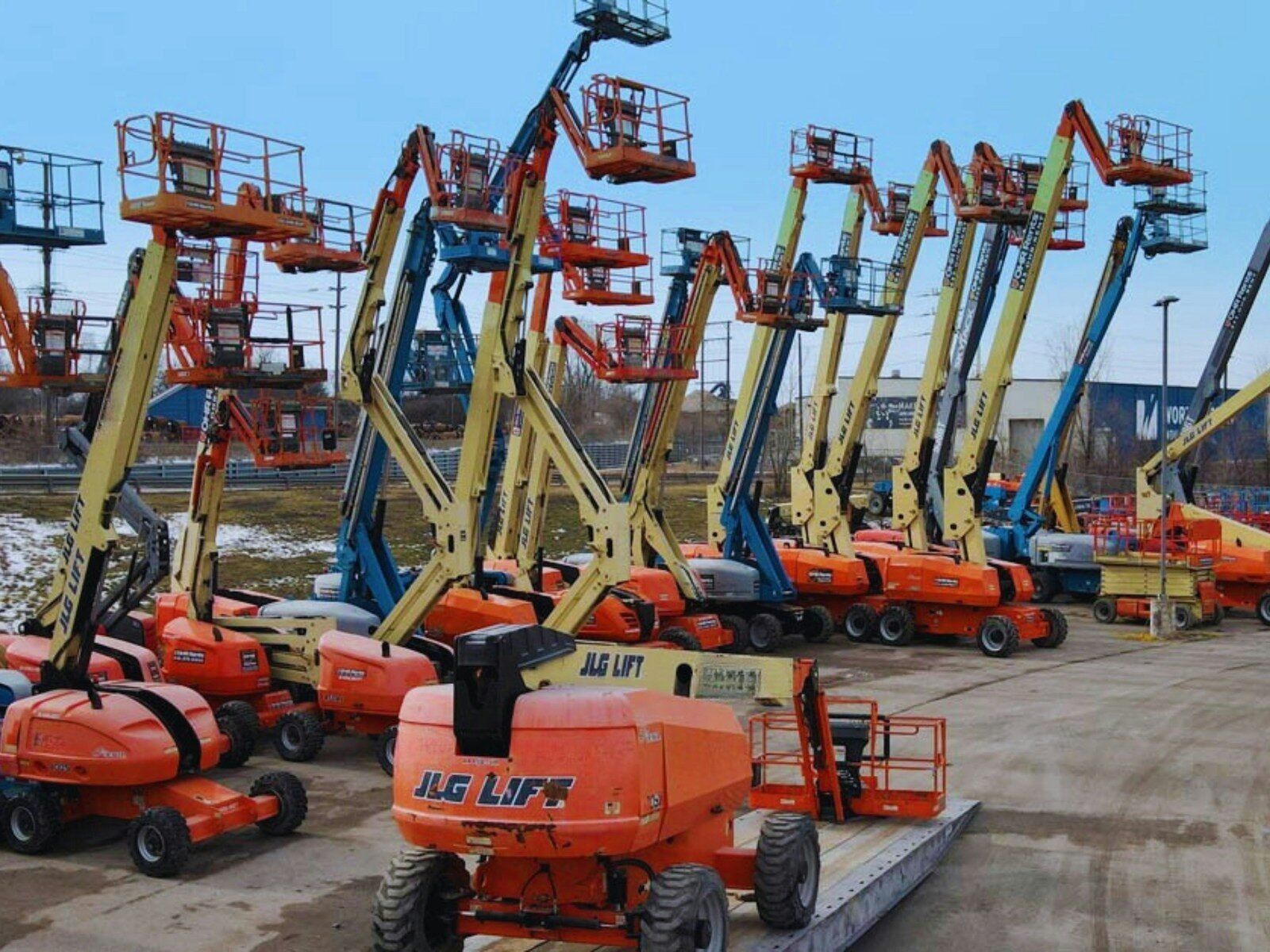Multiple boom lifts parked in an outdoor lot.